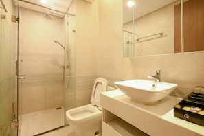 A bathroom with a glass-enclosed shower, a toilet, and a sink with a mirror above it.