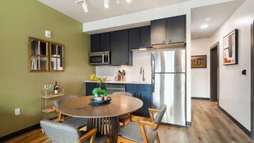 A modern kitchen with dark cabinets, stainless steel appliances, and a round dining table with chairs.