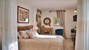 A bedroom with a bed, a desk, a chair, a mirror, and a window with curtains.