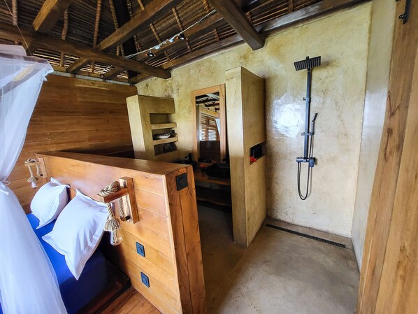 Una habitación rústica de madera con una cama, ducha y pequeña cocina.