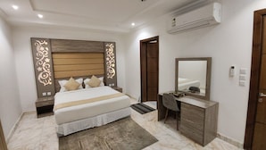 Un dormitorio con cama, mesitas de noche, un escritorio, una silla, un espejo y un equipo de aire acondicionado.