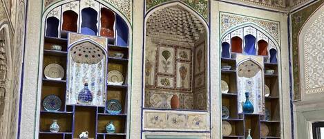 Una habitación de diseño tradicional, con una puerta central flanqueada por estanterías ornamentales y diversos objetos decorativos.