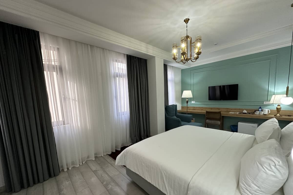 Une chambre d’hôtel avec un grand lit, un bureau avec une lampe, une télévision et un minibar.