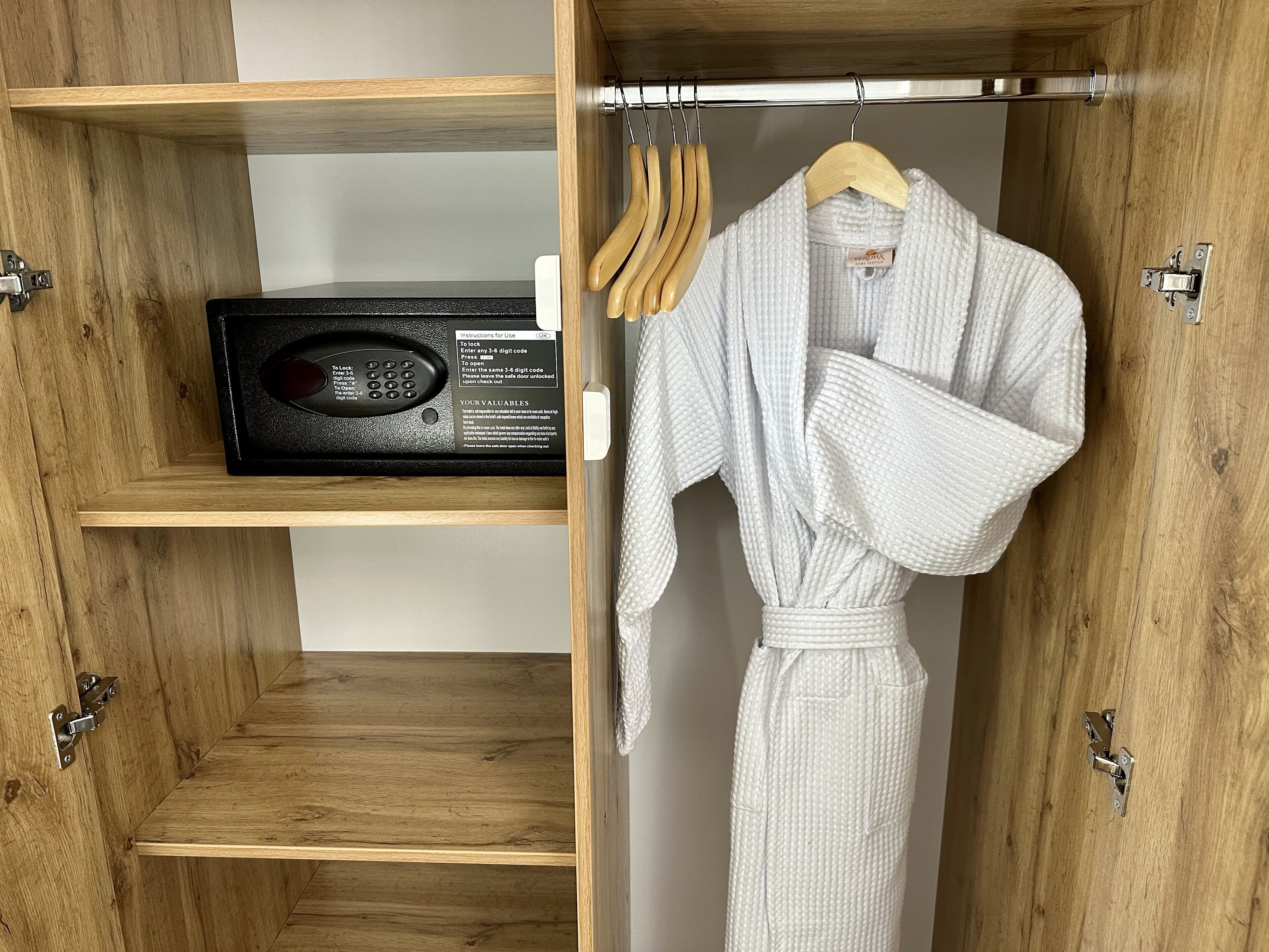 Un armario de madera con una radio, una bata blanca y perchas de madera.