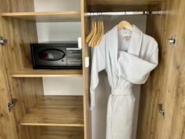 Un armario de madera con una radio, una bata blanca y perchas de madera.