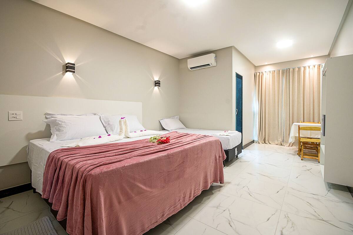 Une chambre d’hôtel avec un lit, des tables de chevet, une chaise et une petite table.