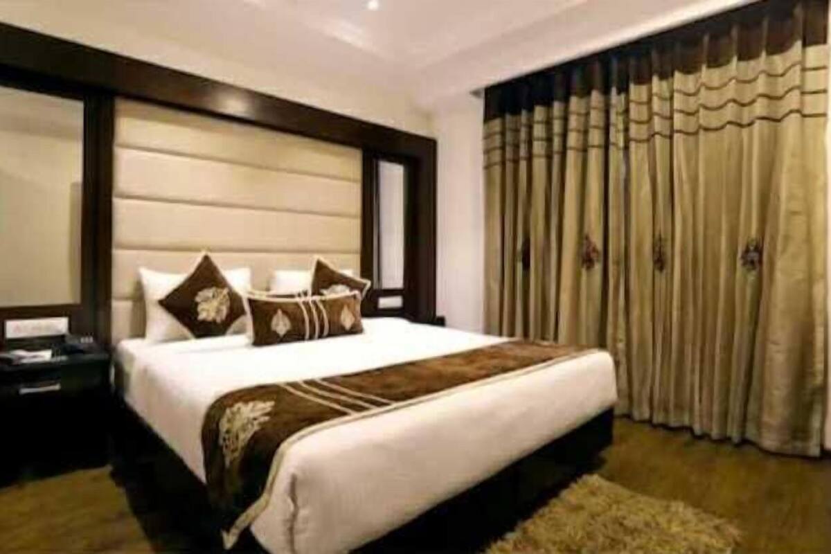 Habitación de hotel con una cama grande, una mesita de noche y una ventana con cortinas.
