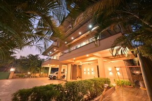Una casa moderna a due piani con un vialetto coperto, un'auto parcheggiata all'interno e un ingresso ben illuminato.