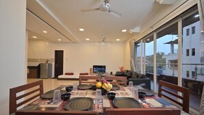A dining area with a table set for four, a ceiling fan, and a TV in the background.