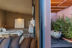 A modern hotel room with a large bed, a bedside table, and a large window.