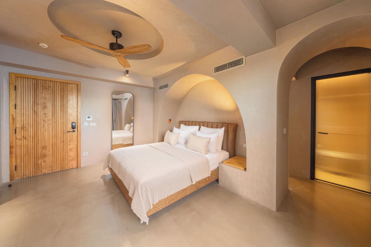 Ein modernes Schlafzimmer mit einem großen Bett, einer Holztür und einem Deckenventilator.