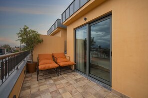 Relax on the balcony with a pair of cushioned chairs and a potted plant, taking in the city view.
