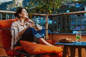 A person sitting on an orange chair with a metal railing, holding a smartphone.