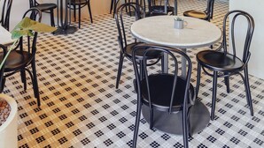 A restaurant interior with round tables and black chairs, a tiled floor, and a staircase leading to an upper level. - Roome (Fethiye)