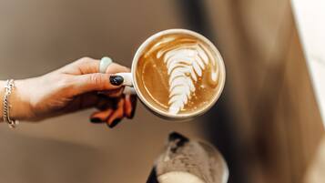 Een hand die een koffiekop vasthoudt met latte art.