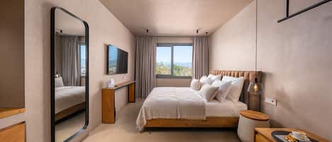 Un dormitorio moderno con una cama grande, una mesita de noche, un espejo, un televisor y una ventana con cortinas.