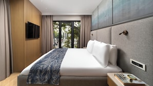 A modern hotel room with a large bed, a flat-screen TV, a wooden panel wall, and a view through a glass door. - Bentley Hotel Old City - Special Class (Istanbul)