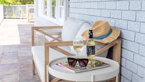 A round table with a magazine, a bottle of wine, and a straw hat. - Adelong - golf and beach lover’s dream (Kiama Downs)