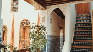 A staircase with patterned tiles, a hanging lantern, and potted plants. - Riad Taj Salma (Fes)