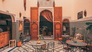 Un patio marroquí con puerta de madera, suelo de baldosas y mobiliario tradicional.