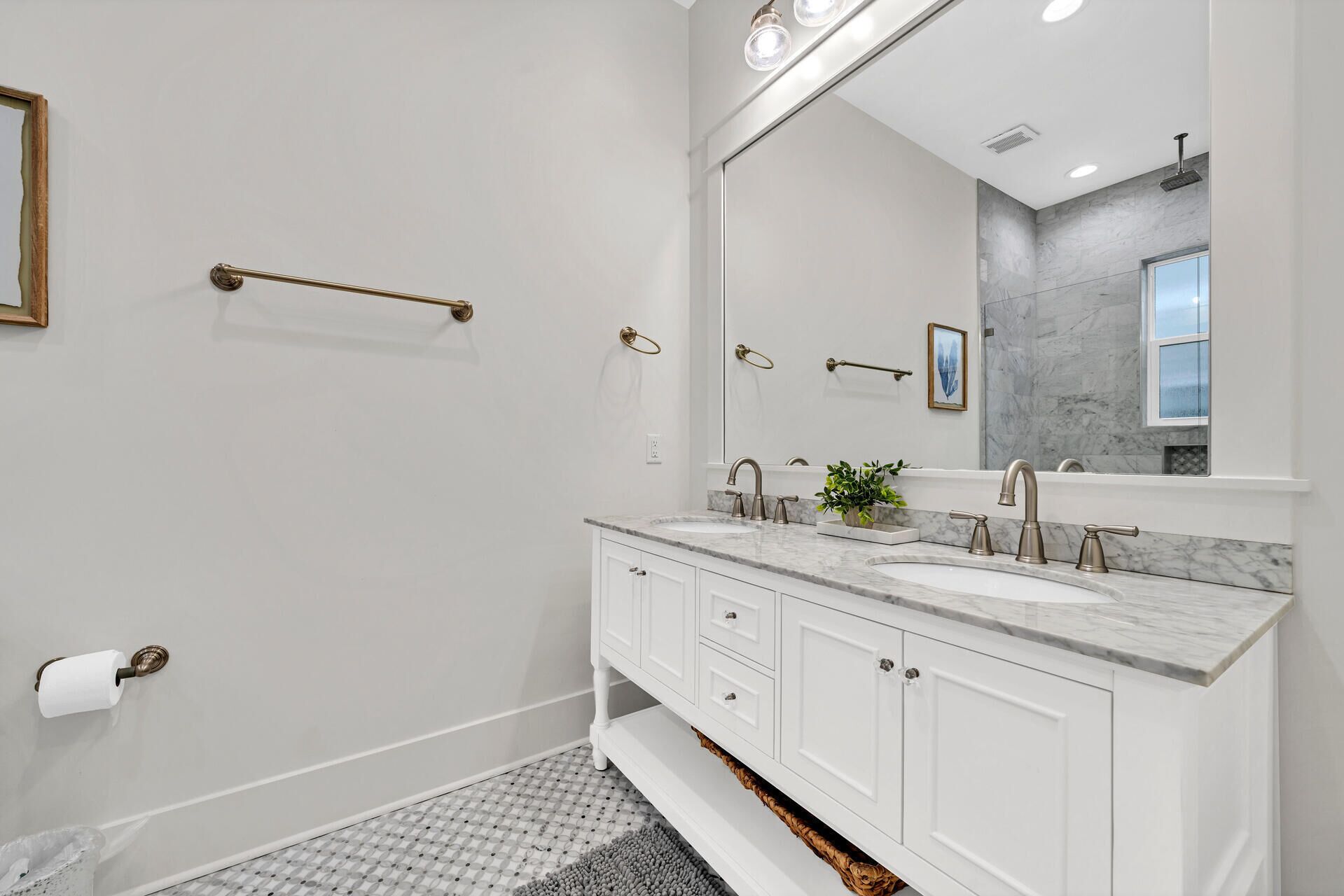 A modern bathroom with a white vanity, a large mirror, and a marble countertop.