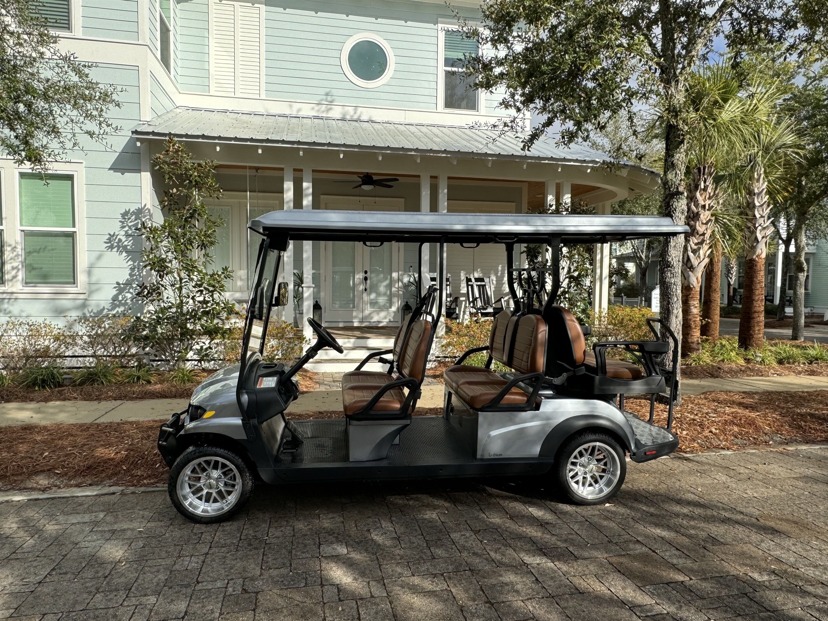 A golf cart parked in front of a house with a porch and a garage.