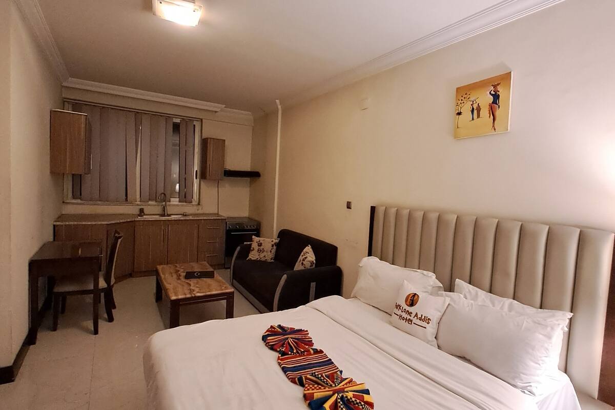 A hotel room with a bed, a desk, a chair, and a sofa.