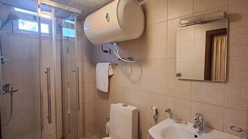 A bathroom with a glass shower enclosure, a toilet, a sink, and a towel rack.