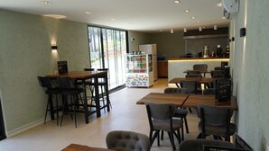 Een modern restaurantinterieur met houten tafels en stoelen, een koelkast met magneten en een menukaartstandaard.