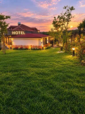 Un hôtel avec un toit rouge, une enseigne indiquant « HÔTEL » et une pelouse bien entretenue.