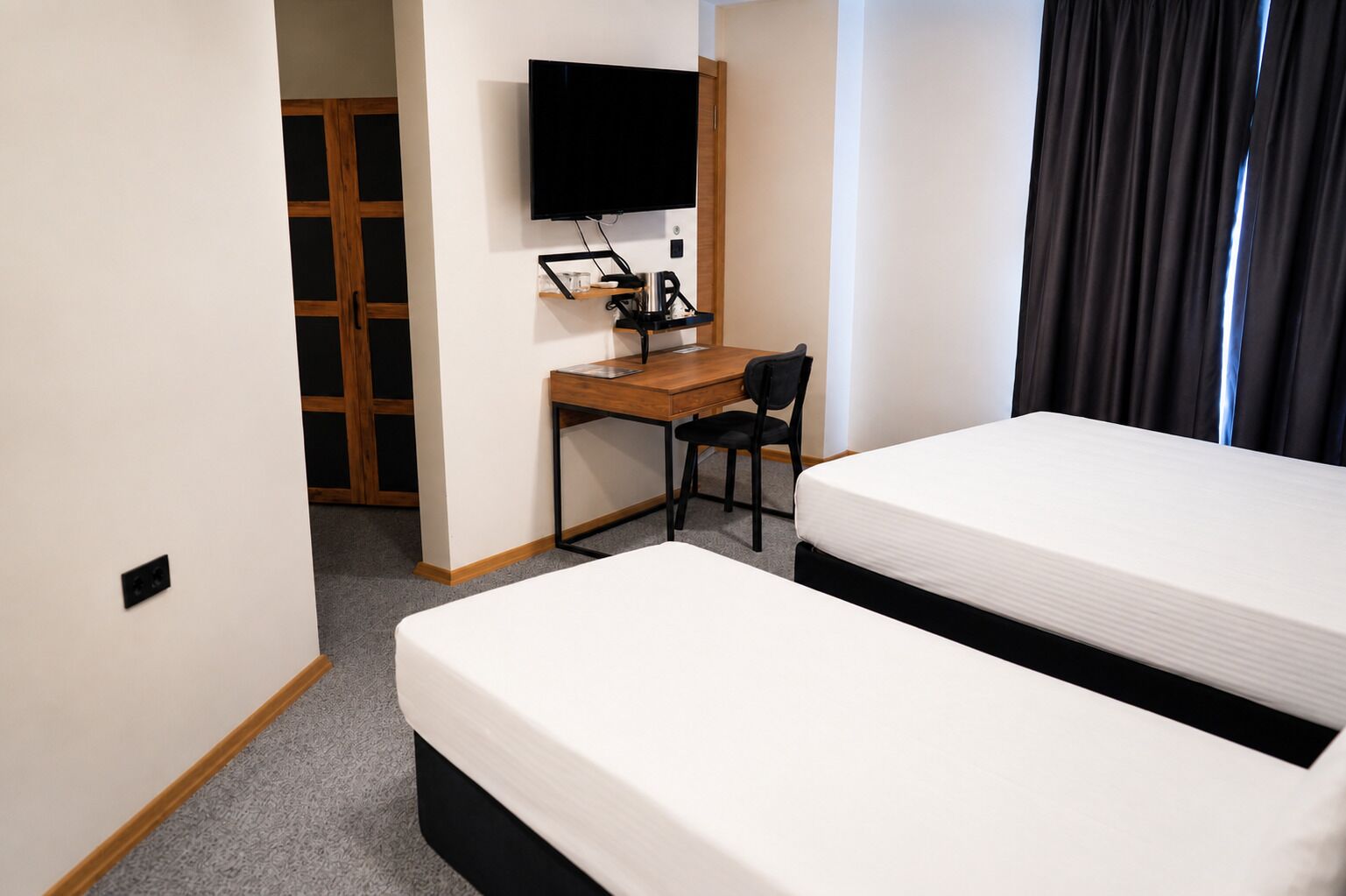 Een hotelkamer met twee bedden, een bureau, een stoel, een televisie en een kledingkast.