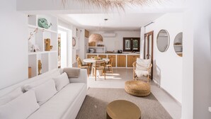 Een moderne, open woonruimte met een witte bank, een eettafel en een keukenhoek.