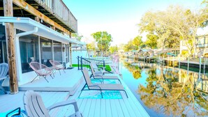 A wooden deck with outdoor seating and a view of a canal. - River home with huge arcade, hot tub, kayaks, mini golf course, 80in TV (Spring Hill)