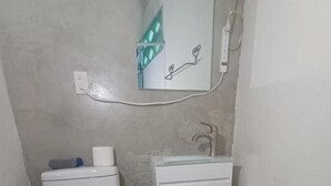 Un baño pequeño con inodoro, lavamanos y espejo.