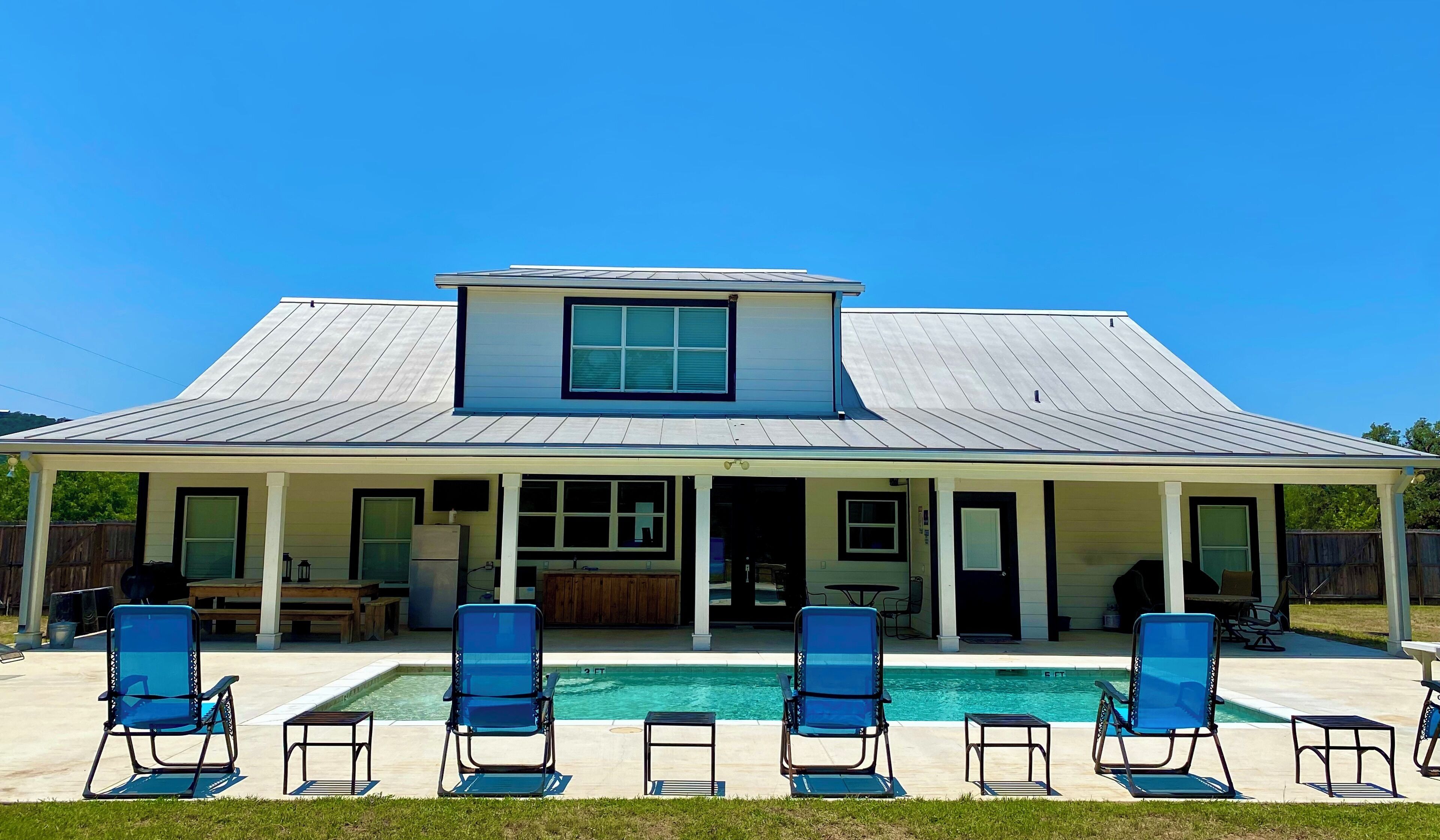 A two-story house with a covered patio and a swimming pool.