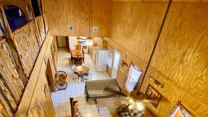 Interior de madera con una escalera, un comedor, un sofá y una pequeña cocina.