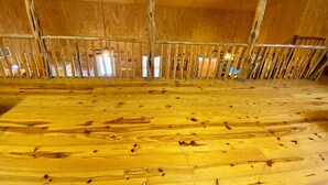 Un dormitorio en el ático con pisos de madera y baranda de metal.