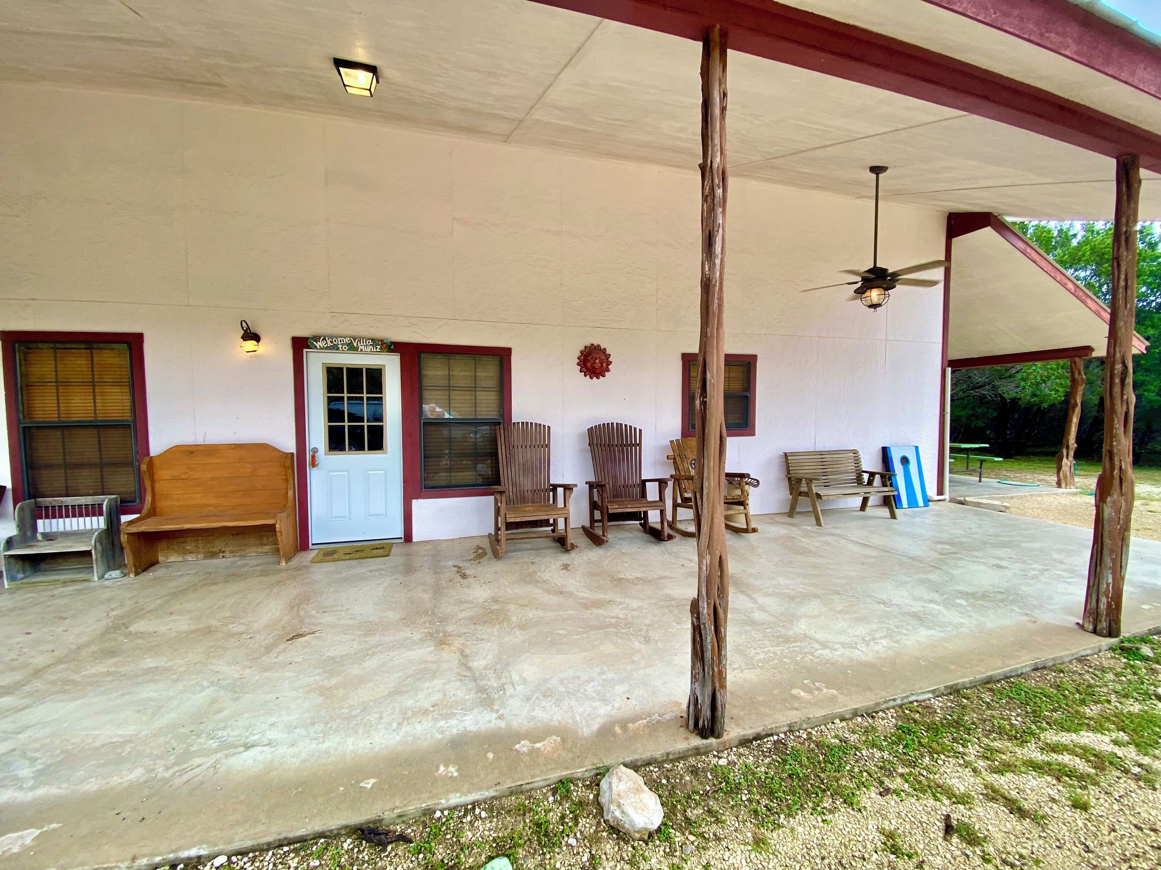 A covered porch with a concrete floor, wooden benches, and a wooden chair.