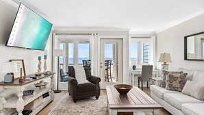 Un salon avec vue sur l’océan, comprenant un canapé, une table basse et un téléviseur fixé au mur.