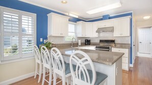 A modern kitchen with white cabinets, a granite countertop, and a central island with bar stools.
