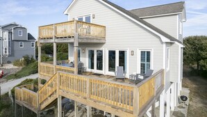 A two-story house with a wooden deck and a balcony.