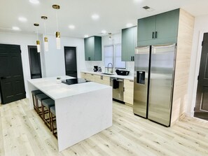 Una cocina moderna con una isla central, electrodomésticos de acero inoxidable y piso de madera clara.