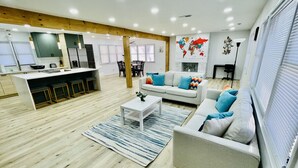 A modern living room with a sofa, coffee table, and a dining area with chairs and a table.