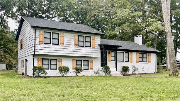A two-story house with a sloped roof, a front porch, and a small front yard.