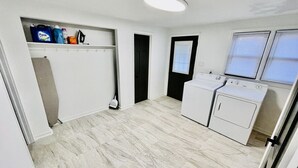A laundry room with a washing machine, a dryer, and a shelf with cleaning supplies.