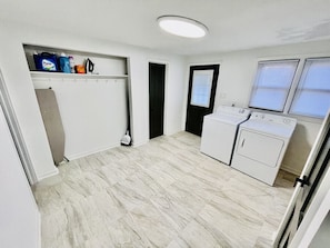 A laundry room with a washing machine, dryer, and storage shelves.