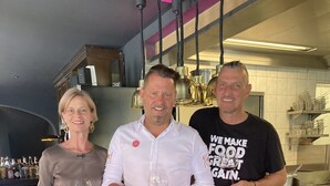 Tres personas en una cocina sosteniendo copas de vino.