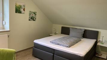 A bedroom with a bed, a nightstand, a lamp, and a radiator.