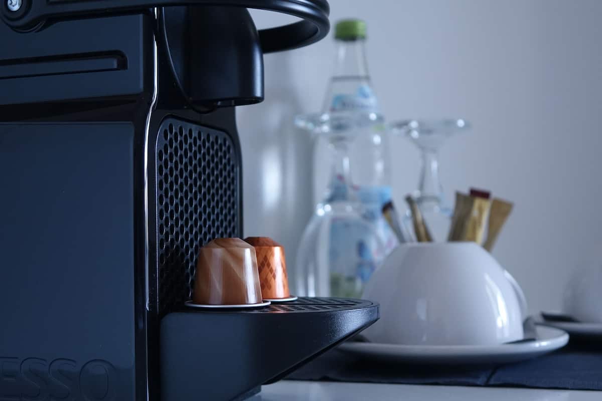 A coffee machine with a cup holder, a water bottle, and a white cup on a table.
