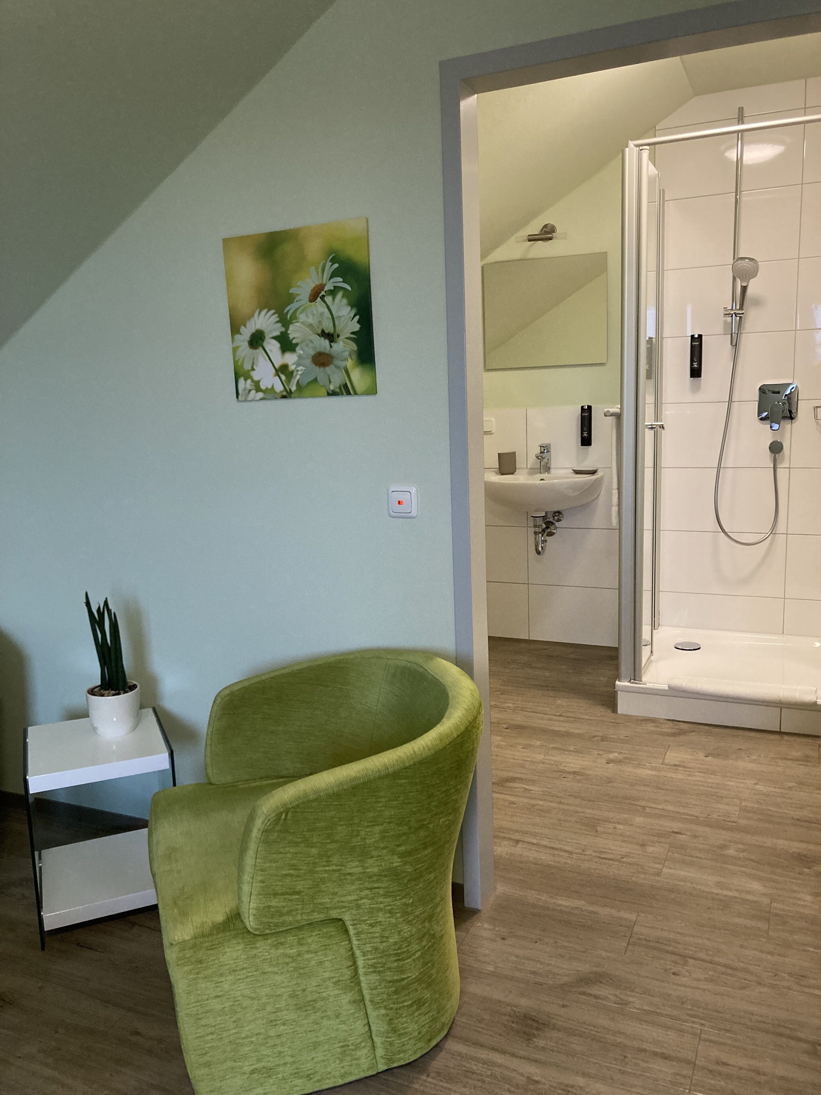 Un baño moderno con ducha, lavamanos y una silla verde.